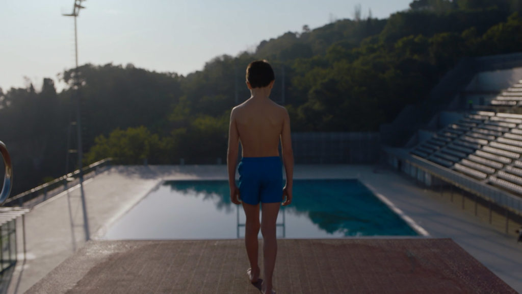Young kid concentrating before jumping into a swimming pool