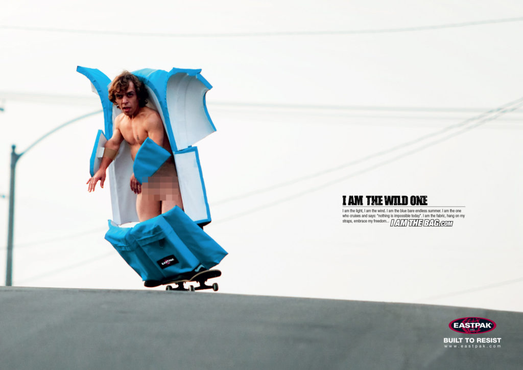 Naked dwarf disguised as an Eastpak bag doing a downhill on a skateboard